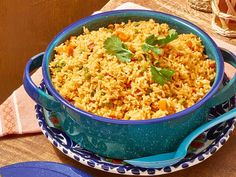 a blue bowl filled with rice on top of a wooden table