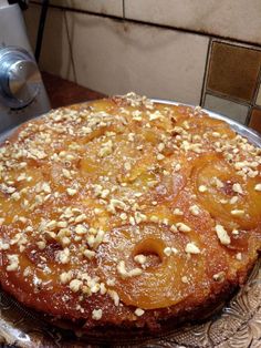 a cake sitting on top of a glass plate covered in nuts and powdered sugar