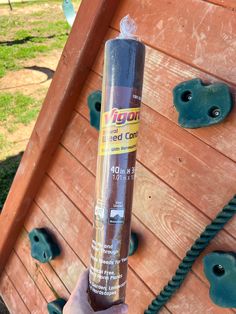 someone holding up a tube of glue on top of a wooden structure with other items in the background