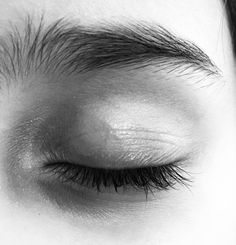 the eye of a person with very long lashes and no makeup is seen in this black and white photo