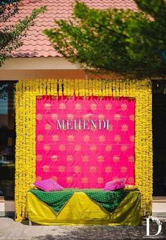 a pink and yellow backdrop with the word mehend on it in front of a building