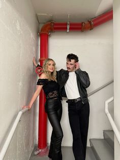 a man and woman are posing for a photo on the stairs in front of a red pipe