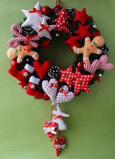 a christmas wreath hanging from the side of a green wall with red and white decorations