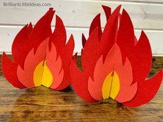 two paper flames sitting on top of a wooden table