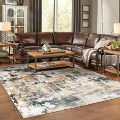 a living room filled with furniture and a large rug on top of a hard wood floor