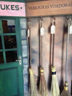 three brooms are hanging on the wall in front of a storefront with an advertisement for vassouras voadoras