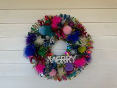 a colorful wreath hanging on the side of a building that says happy new year with pom - poms