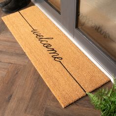 a welcome mat with the word welcome on it next to a potted green plant