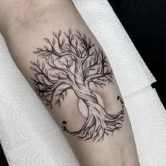 a black and white tree tattoo on the arm