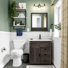 a white toilet sitting next to a wooden sink vanity in a bathroom under a mirror