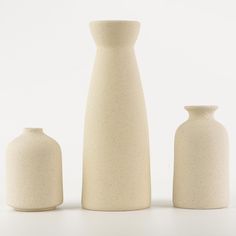 three white vases sitting next to each other in front of a white background,