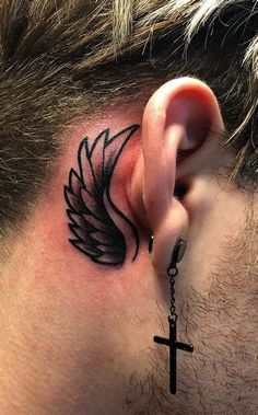 a man with a cross behind his ear and an angel wing tattoo on the back of his ear