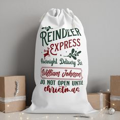 a white bag with red and green lettering on it sitting next to some christmas presents