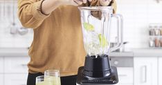 a woman is using a blender to make green smoothies in her kitchen area