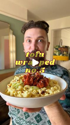 a man holding a bowl of pasta with meat and sauce on it in front of the camera