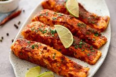 chicken wings with limes and spices on a white plate next to a small bowl