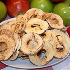 sliced apples are sitting on a plate next to green apples and red checkered table cloth