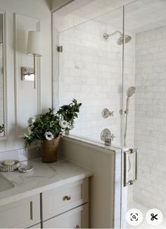 a bathroom with a sink, mirror and shower in it's corner next to a counter