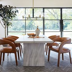 a dining room table with chairs around it and a vase sitting on top of the table