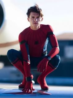 a man in a red spider suit crouches down