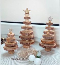 three wooden christmas trees with stars on top and balls in the middle, sitting on a mat