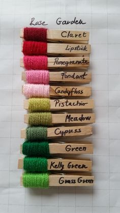 several different colored spools of yarn sitting on top of wooden clothes pegs