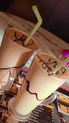 two drinks with straws sitting next to each other