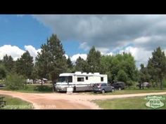 an rv park with cars parked on the side and trees in the backgroud