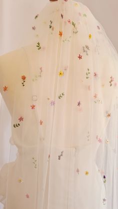 the back of a white dress with colorful flowers and butterflies on it's sheer fabric