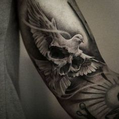 a man's arm with a bird and skull tattoo on it