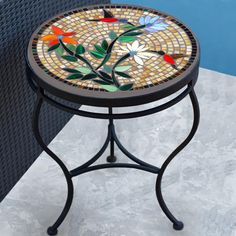 a small mosaic table sitting on top of a tiled floor next to a swimming pool