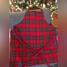 a red and black plaid apron sitting on top of a couch next to a christmas tree