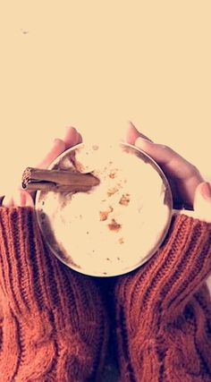 two hands holding a bowl of food with cinnamon sticks sticking out of it