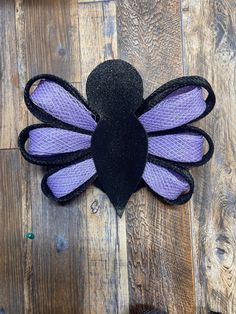 a purple and black flower on top of a wooden floor