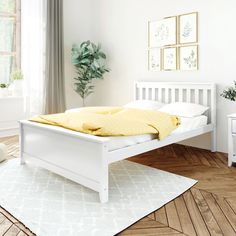 a white bed sitting on top of a hard wood floor next to a table with a potted plant