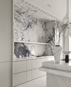 a kitchen with marble counter tops and white cabinets in the corner, along with a vase filled with flowers