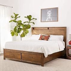 a bedroom with a bed, dresser and potted plant