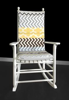 a white rocking chair with yellow and gray pillows on it's backrests