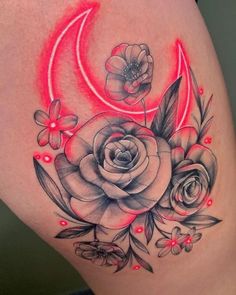 a woman's thigh with flowers and a crescent tattoo