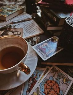 a cup of coffee sitting on top of a table filled with books and tarot cards