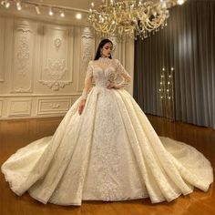 a woman in a white wedding dress standing next to a chandelier