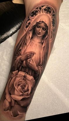 a woman with a rosary and rose tattoo on her arm is shown in black and white