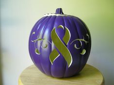 a purple and gold painted pumpkin sitting on top of a wooden table