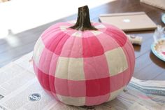 a pink and white checkered pumpkin sitting on top of a table next to a laptop