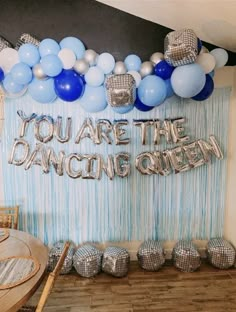 balloons and streamers decorate the backdrop for a dance queen themed birthday party in blue, silver and white