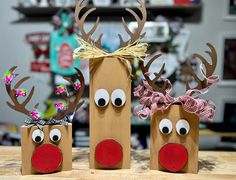 three paper bags with reindeer noses and bows on them, sitting on a wooden table