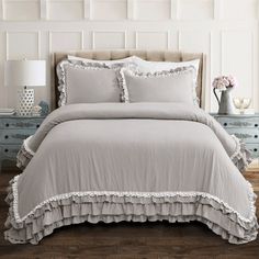 the comforter is made up with ruffles on it and pillows in grey