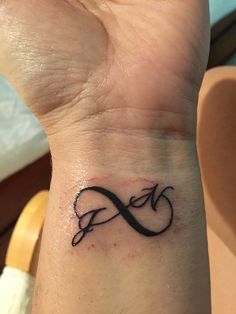 a small wrist tattoo with an infinite symbol on the left side of the wrist, in black ink