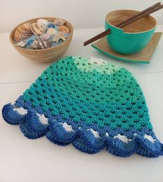 a crocheted dishcloth sits on a table next to a bowl of seashells