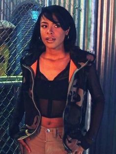 a woman standing in front of a chain link fence